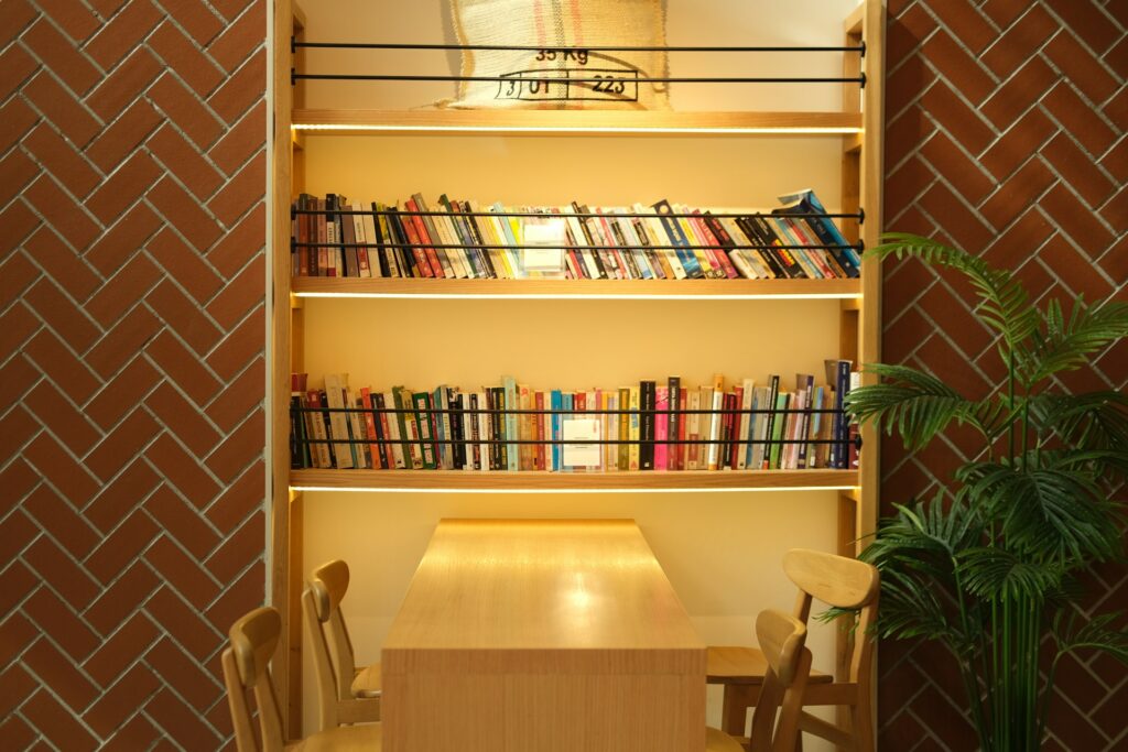 Modern wooden corner bookshelf in a cozy living room with books and plants.