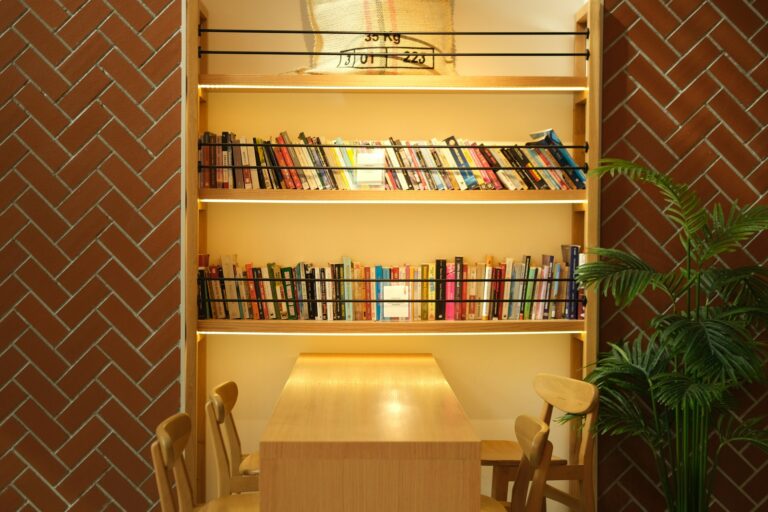 Modern wooden corner bookshelf in a cozy living room with books and plants.